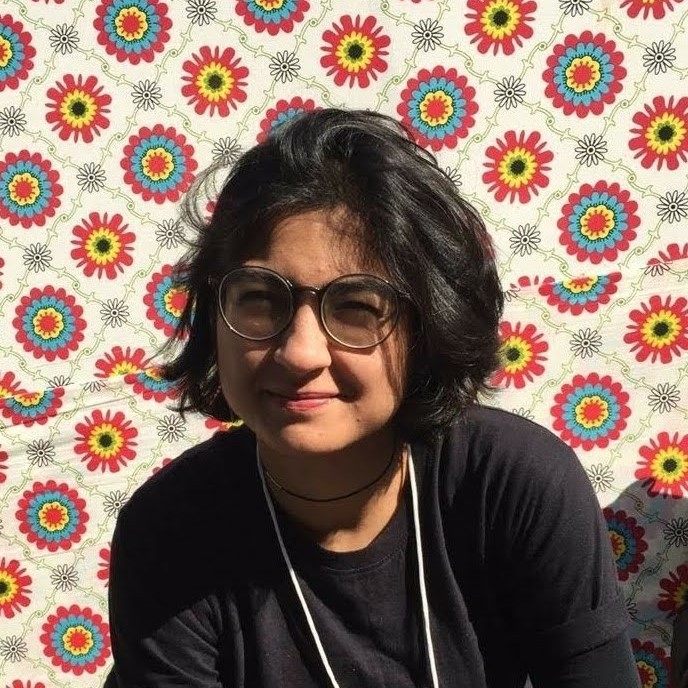 Mekhala Singhal looks at camera wearing glasses in front of patterned wall